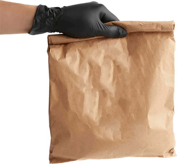 Hand mit Schutzhandschuh hält Papiertüte